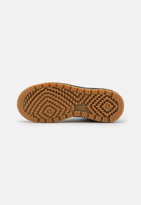 Shoe sole with a patterned design; features a combination of black and gum rubber. Textured for grip with various geometric shapes.
