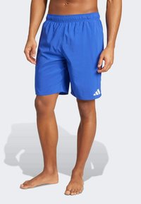 Bañador deportivo azul con cintura elástica, textura suave y un acento de logo blanco en la parte inferior de la pierna izquierda.