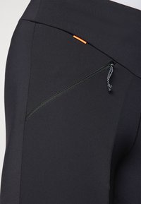 Čierne športové legíny s bočným zipsovým vreckom, ťahákom na zips a oranžovým akcentovým štítkom. Vyrobené z hladkého, elastického materiálu.