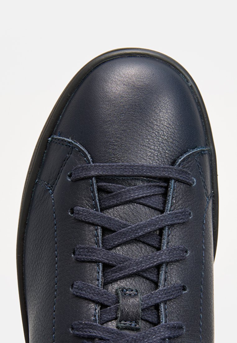 Granatowe skórzane buty z zaokrąglonym czubkiem, teksturowaną powierzchnią i płaskimi sznurówkami. Posiadają przeszycia oraz gładkie wykończenie w górnej części.