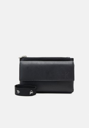 Black leather clutch with front flap, zipper closure, and detachable black fabric strap branded with white "cK" logos.