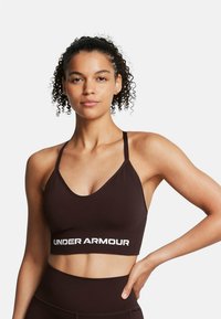 Bruin sportbeha met een brede band met daarop de witte tekst "UNDER ARMOUR". Verstelbare dunne bandjes, zachte stof en een slank ontwerp.