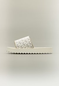 Λευκό σανδάλι με πλατφόρμα και σόλα ζιγκ-ζαγκ, με φαρδιά λουράκι που φέρει επαναλαμβανόμενο αφηρημένο μοτίβο σε γκρι αποχρώσεις.