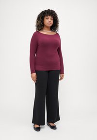 Long-sleeve burgundy top with a scoop neckline, paired with black wide-leg pants and black flats, featuring a smooth texture and fitted design.