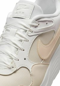 Vita sportskor med en slät läderöverdel, satin-snören och en ljusbeige swoosh-logotyp. Sytt detaljer runt panelerna.