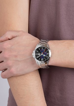 Montre en acier inoxydable argenté avec un cadran noir, comprenant trois sous-cadrans bleus, des index argentés et un bracelet à maillons.