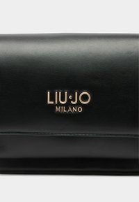 Portafoglio in pelle nera con texture liscia, logo in oro impresso e linee pulite. Design rettangolare compatto con chiusura piegata.