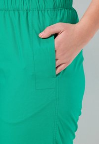 Gr�üner, leichter Stoff mit einem elastischen Bund, ausgestattet mit einer Seitentasche und glatter Textur. Die Nähte sind entlang der Seitennähte sichtbar.