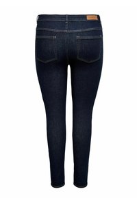 Σκούρο μπλε στενά τζιν από denim, με λεία υφή, σχεδίαση με πέντε τσέπες και ραμμένες ραφές με δερμάτινη ετικέτα μάρκας στο πίσω μέρος.