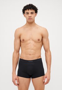Čierne bavlnené boxerky s širokým elastickým pásom, na ktorom je logo "SLOGGI". Hladká textúra a priliehavý strih.