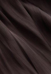 Tissu brun foncé lisse avec des plis doux et une texture de tissage visible.