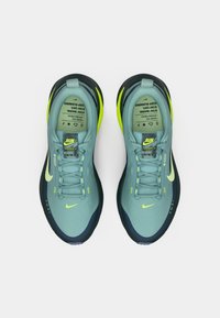 Αθλητικά παπούτσια τρεξίματος Nike σε ανοιχτό μπλε και σκούρο ναυτικό. Διαθέτουν νέον κίτρινες λεπτομέρειες, υφασμάτινο επάνω μέρος με υφή και ανακλαστικά στοιχεία branding.