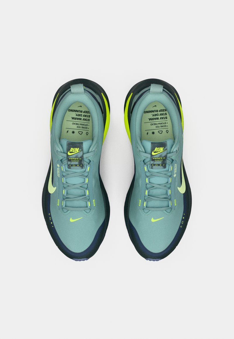 Nike Laufschuhe in Hellblau und Dunkelblau. Merkmale sind neon-gelbe Akzente, ein strukturierter Stoffoberteil und reflektierende Branding-Elemente.