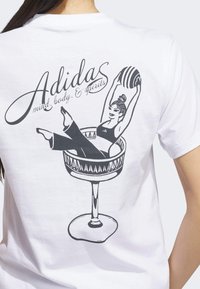 Bílé bavlněné tričko s černou grafikou ženy v koktejlové sklenici, nad kterou je nápis "Adidas mind, body, & spirits".