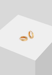 Guld hoopsøreringe med en tekstureret overflade og et simpelt hængseldesign, der har en glat, poleret inderside.