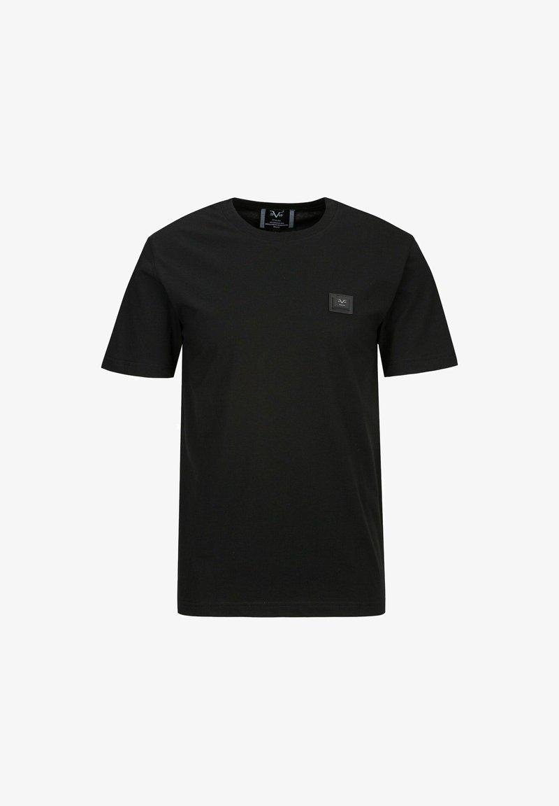 Schwarzes Baumwoll-T-Shirt mit rundem Halsausschnitt, kurzen Ärmeln und einem kleinen quadratischen Logopatch auf der linken Brust. Glatte Textur, reguläre Passform.