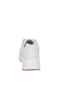 Zapatilla deportiva blanca con una parte superior lisa, acentos perforados y una suela de goma que contrasta. Forma redondeada con talón acolchado.