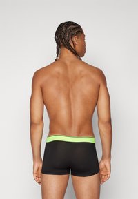 Black boxer shorts with a green waistband, featuring a smooth texture and a snug fit, viewed from the back. No additional details visible.