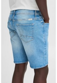 Shorts en denim bleu clair avec une finition légèrement délavée, design à cinq poches et coutures contrastantes. Présente une coupe slim classique et des ourlets roulés.