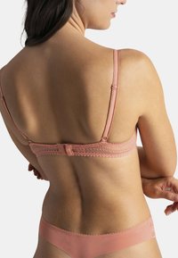 Soutien-gorge bralette en dentelle rose doux avec bretelles réglables et fermeture au dos, associé à un bas de bikini assorti avec une finition lisse.