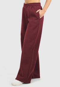 Bordeaux joggings met een wijduitlopende pasvorm, een elastische tailleband, zijzakken en zichtbare stikdetails. Zacht katoenmixmateriaal.