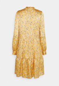 Robe jaune à manches longues avec motif floral noir et blanc, taille froncée, tissu plissé et jupe à étages.