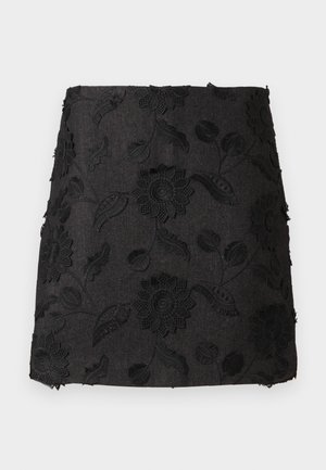 Schwarzer Leinenrock mit bestickten floralen Mustern in unterschiedlichen Texturen, mit einer figurbetonten Form und leicht ausgefranstem Saum.