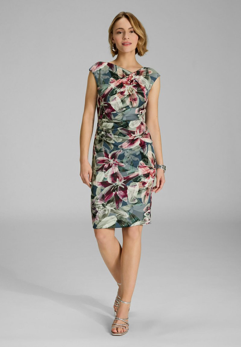 Blumenmusterkleid mit kurzen Ärmeln, das einen grünen Grundton mit rosa und weißen Blumen aufweist, seitliche Raffung und knielangen Schnitt.