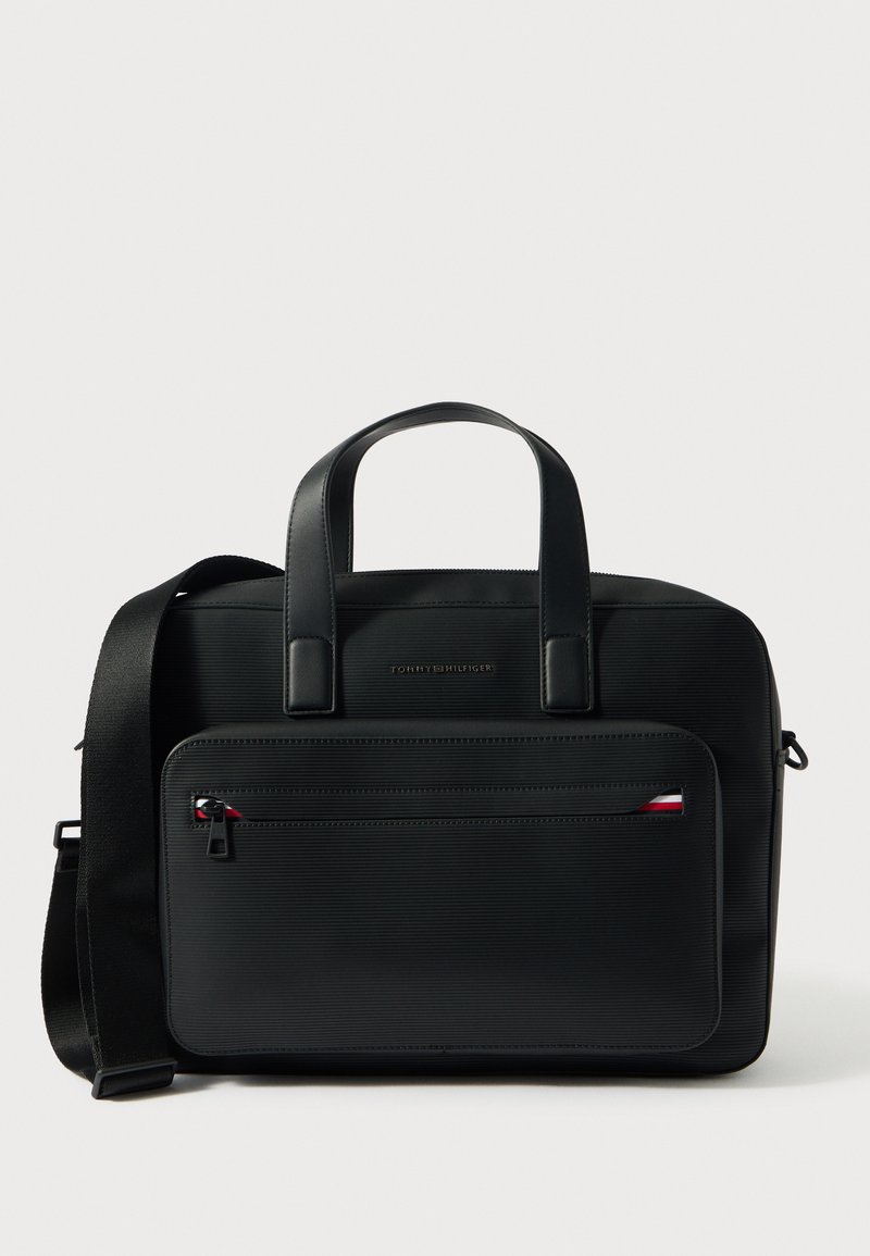 Melna klēpjdatora soma ar virsmas faktūru, diviem rokturiem, regulējamu plecu siksnu, priekšpusē rāvējslēdzēja kabatu un nelielu logotipa detaļu.