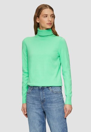 Mintgrüner Rollkragenpullover aus weichem Strickstoff, mit langen Ärmeln und enganliegendem Design. Kombiniert mit hellblauen Jeans.