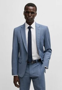 Lichtblauw twee-delig pak met een subtiel ruitpatroon, gecombineerd met een wit overhemd en een donkerblauwe stropdas. Heeft een slim fit en notch revers.