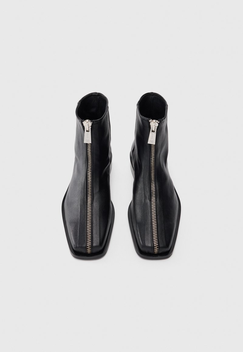 Bottines noires en cuir avec un bout carré et une fermeture éclair argentée sur toute la longueur à l'avant. Texture lisse et design épuré.