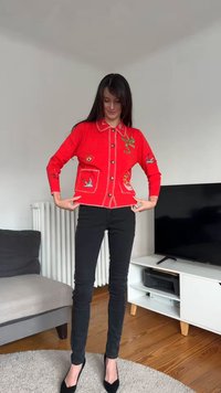 Rød strikket cardigan pyntet med forskjellige broderte motiver, inkludert fugler og en dekorativ slange, med knappestenging og kontrasterende krage.