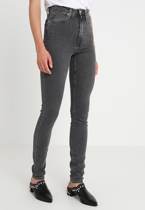Jeans de tiro alto y corte ajustado en denim gris oscuro, con un diseño clásico de 5 bolsillos y costuras en contraste. Silueta resaltada por la parte delantera plana.