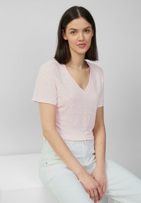 Roze korte mouwen V-hals T-shirt van lichtgewicht katoen, met een relaxte pasvorm en subtiele textuur. Draag met lichtblauwe hoge taille broek.