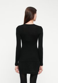 Black ribbed long-sleeve top with a fitted silhouette, featuring a round neckline and a contrasting textured black hem.