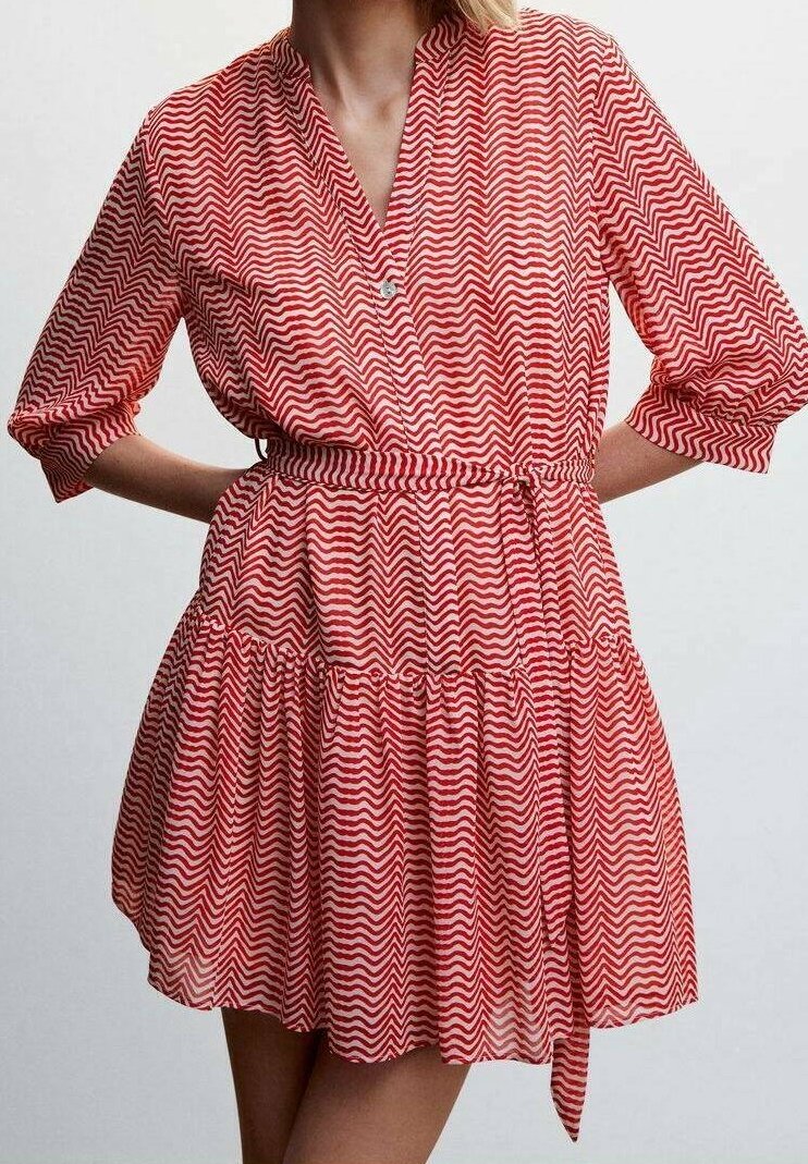 Femme portant une robe à motif zigzag rouge et blanc avec des manches trois-quarts et une ceinture nouée à la taille.