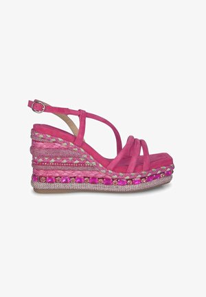 Sandalo con tacco a cuneo in suede rosa, caratterizzato da dettagli intrecciati, ornamenti gioiello lungo la suola e sottili cinturini incrociati per una vestibilità sicura.
