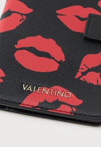 Portafoglio in pelle nera con texture, stampa di labbra rosse e logo dorato "VALENTINO". Caratterizzato da un design elegante e compatto, ideale per l'uso quotidiano.