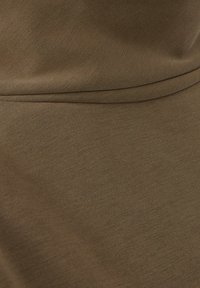 Brunt tyg med en slät textur, som har en subtil stretch. Materialet verkar lätt med en matt yta och minimal sömnadsdetalj.