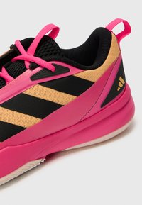 Sportssko med en overdel i sort og gul mesh, pink accenter og sorte striber. Har en polstret krave og gummisål for godt greb.
