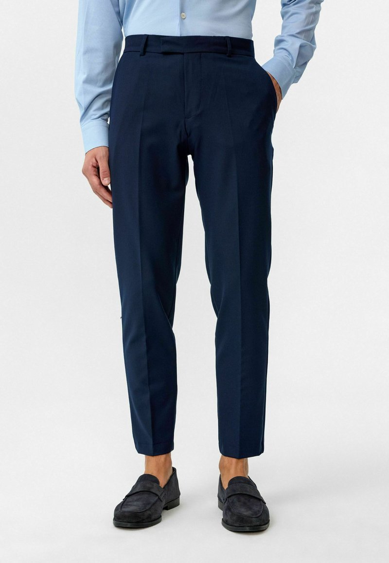 Navyblauwe broek met een slim fit, met een vlakke voorkant, zijzakken en een soepele textuur. Gecombineerd met donkere instappers.