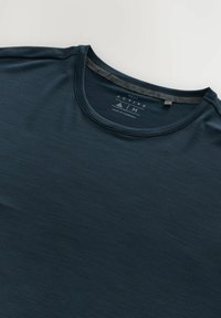 Camiseta de deporte en azul marino oscuro, con cuello redondo, textura suave y patrones sutiles. Etiqueta en el interior que identifica la marca y el origen.