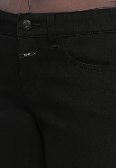 Schwarze Denim-Jeans zeichnen sich durch ein enganliegendes Design mit einem klassischen Knopfverschluss, dezenten Nähten und einem Logetikett im Taillenbereich aus.