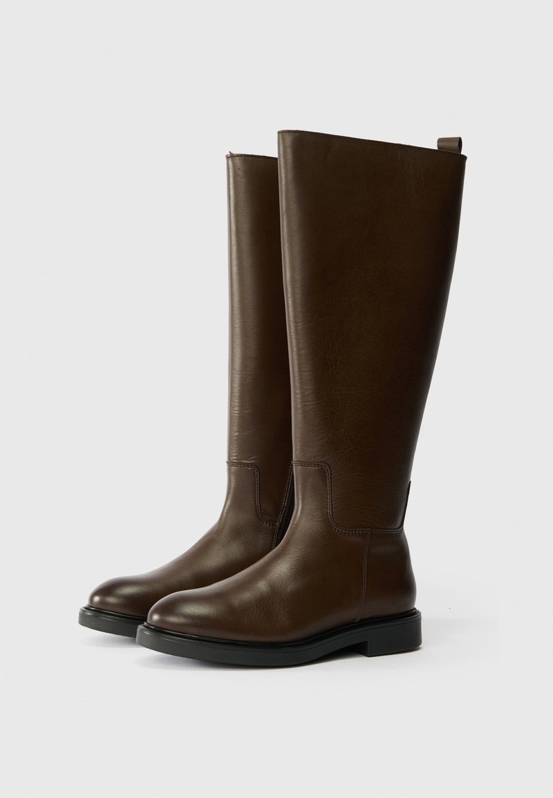 Stivali alti in pelle marrone, con una texture liscia, punta arrotondata e suola piatta. Presentano un delicato design cucito e un comodo laccio per indossarli.