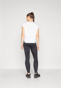 White short-sleeve top paired with black leggings. The top features a loose fit, and the leggings are form-fitting with a smooth texture.