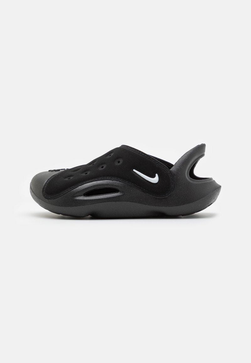 Black athletic shoe with a smooth, rubbery texture, featuring ventilation holes, a curved design, and a white Nike logo on the side.