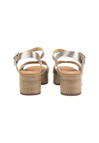 Sandalias de tacón abiertas con una parte superior de cuero metálico plateado, tira ajustable en el tobillo y un tacón de bloque de madera texturizada.