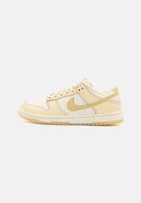 Beige Nike Dunk-sneakers med en tekstureret overdel, glatte læderdetaljer og en gummisål. Har en fremtrædende swoosh og tonale snørebånd.
