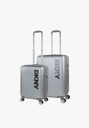 Set de equipaje rígido plateado, con acabado texturizado y logo DKNY en relieve. Equipado con asas retráctiles y ruedas giratorias.